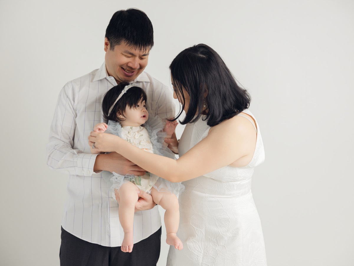 Jason and his wife holding their baby daughter, smiling down at her